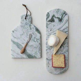 Two-piece marble cheese board set with a canape knife on the left board and cheese wedges on the right