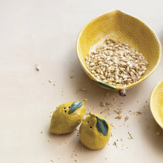 Two hand-painted lemon-shaped salt and pepper shakers in yellow ceramic with green leaves