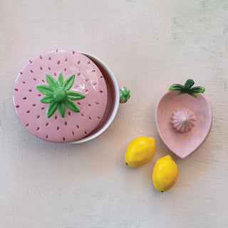 Strawberry-shaped stoneware juicer, hand-painted pink with green leaf lid, lemons nearby.