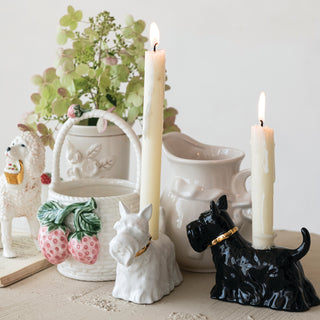 Ceramic Scottie dog taper candle holder pair in white and black with gold collars, holding tall ivory candles.
