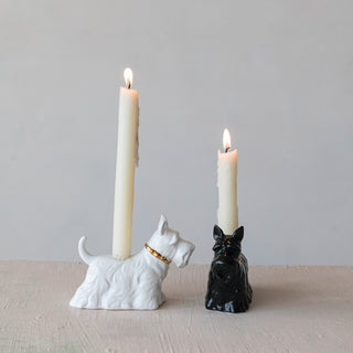 Two ceramic Scottie dog taper candle holders in white with gold collar and black finish, each holding a candle.