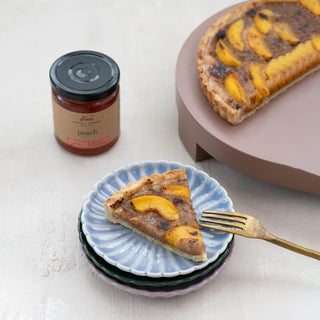 9 oz peach jam jar beside peach-topped tart slices on pastel plates
