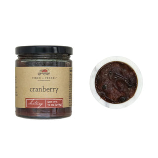 Cranberry chutney sauce in a 10 oz glass jar beside a bowl of dark chutney (2 items)