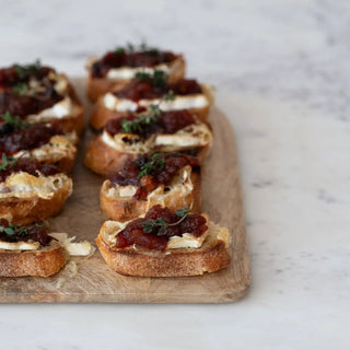 Cranberry chutney sauce on bite-sized crostini with cream cheese and thyme garnish
