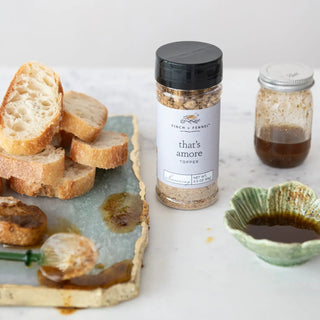 That's Amore Topper Seasoning bottle, 3.3 oz, with a black cap, beside a second jar and sliced bread.
