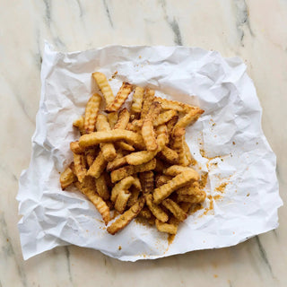 That's Amore Topper Seasoning on crinkle-cut fries; golden-brown, lightly dusted with orange spice.