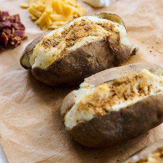 That's Amore Topper Seasoning on loaded baked potatoes with melted cheese and brown seasoning dust