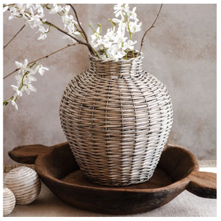 Grey Willow Vase, woven wicker, on a wooden tray with white flowers.