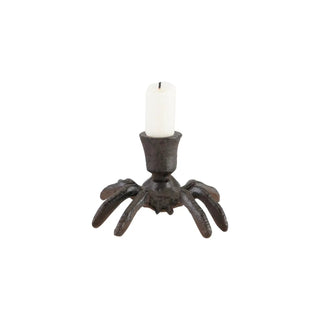 Cast iron spider-shaped taper candle holder holding a white candle