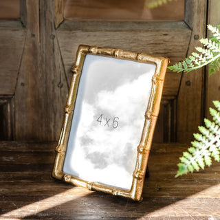Gold bamboo-style photo frame with 4x6 opening on a rustic wooden surface.