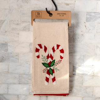 Candy cane dish towel on natural beige fabric with red-and-white candy cane pattern and red pom trim
