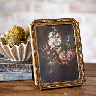 Antique gold dot-edge photo frame with beaded border holding floral artwork.