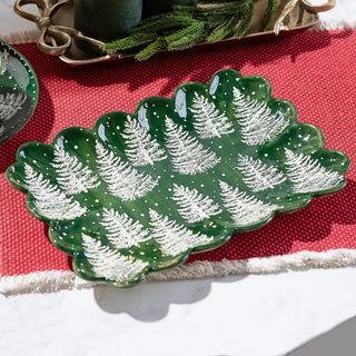 Tree Print Plate, green with white tree silhouettes and scalloped edge; part of a set on a red table runner.