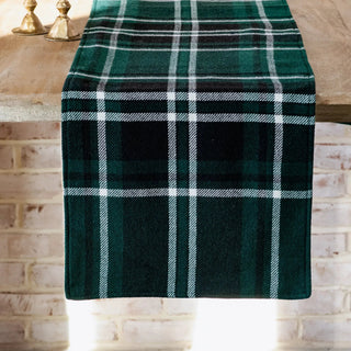 Green tartan table runner on a wood table with white plaid stripes.