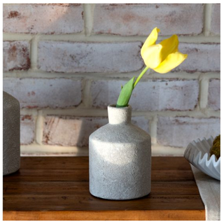 Sandy white textured ceramic vase with a short neck holding a yellow tulip.