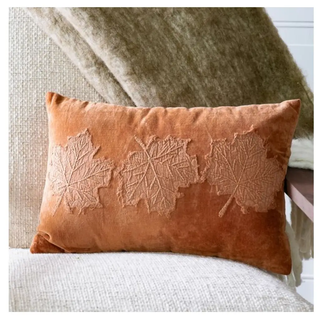 Velvet burnt-orange leaf pillow with an embroidered leaf motif.