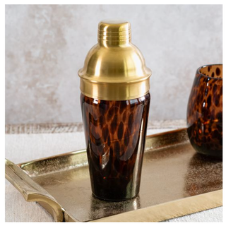 Tortoise shell shaker with gold lid, amber glass body on a metallic gold tray