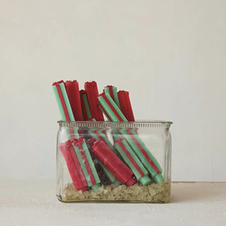 Taper candles, green and red, unscented package-shaped, arranged in a glass jar.