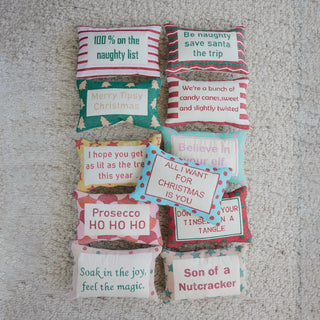 Set of twelve cotton embroidered lumbar pillows with festive quotes and red, teal, and green polka-dot accents