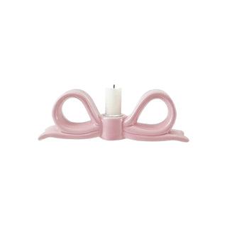 Ceramic bow-shaped taper candle holder in pink with white candle.