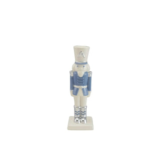 Nutcracker-shaped ceramic taper candle holder in white and blue with silver accents.