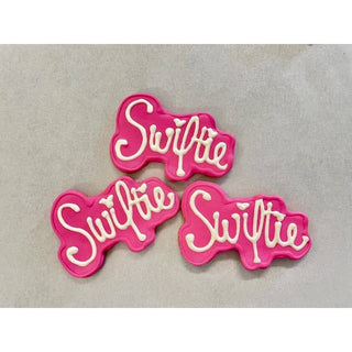 Swiftie Era Dapper pink pet cookies with white icing forming Swiftie script, three treats