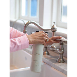 Fresh Linen multipurpose cleaner bottle, white plastic with visible brand label, held near a kitchen sink faucet.