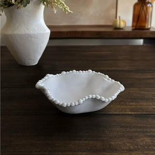 Mini white wavy bowl with a beaded edge, displayed on a dark wood table in a home setting, ideal for serving snacks.