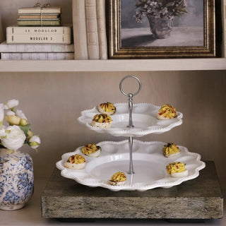 Two-tier white ceramic egg server on a pedestal with a silver central handle