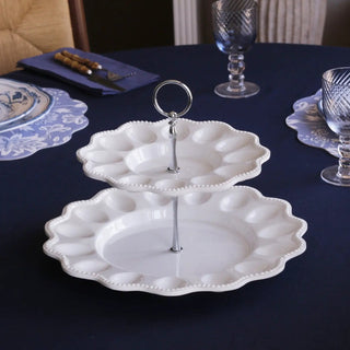 Two-tier white ceramic egg server on a silver pedestal with ring handle