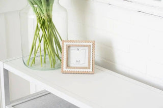 Wood scalloped photo frame for 4x4 pictures, natural with white inner border, on a white shelf beside a glass vase.