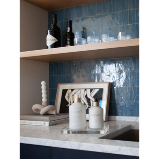 Lucite tray on a marble countertop holding two white lotion bottles with gold caps