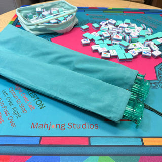 Lunaflor Mahjong Mat in turquoise with one mint-green zippered pouch and scattered tiles.