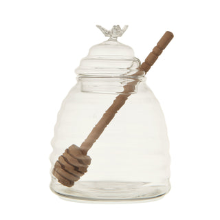 Glass honey jar with lid and wooden honey dipper for serving honey