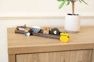 Six 2x2 inch wooden cooking shapes on a dark wood display rail, including a blue polka-dot bowl and a yellow pot.