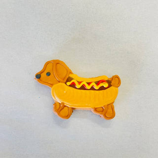 Dog-shaped cookie with orange icing and hot dog bun design, yellow mustard and red ketchup accents