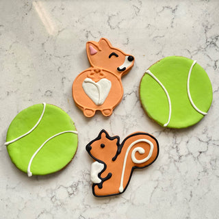 All the Dog Things Dapper cookies: two green tennis-ball cookies and two orange dog-shaped cookies