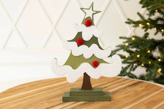 Wood Christmas tree cutout on stand ornament, 5x7x2, green with white flocked snow and red accents.