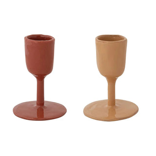 Two enameled cast-iron taper holders in red and beige with round bases.