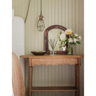 Reed diffuser Fresh Linen in a clear glass bottle with black reeds on a rustic wooden table.
