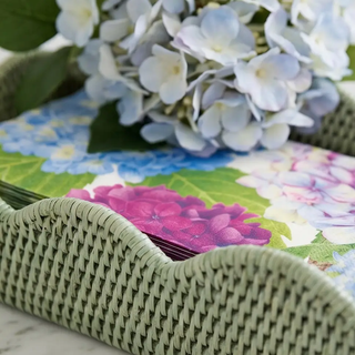 Blue hydrangea hostess gift set arranged in a green wicker basket atop a colorful floral table runner.