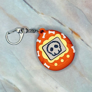 Round orange keychain with a skull design on a light marble background