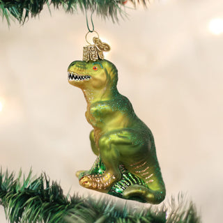 T-rex ornament, glittery green dinosaur Christmas decoration with a metallic cap, hanging from a Christmas tree