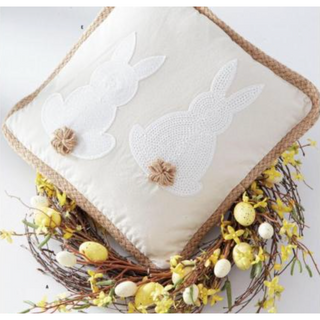 Square tan throw pillow by K&K with two white embroidered Easter bunny silhouettes